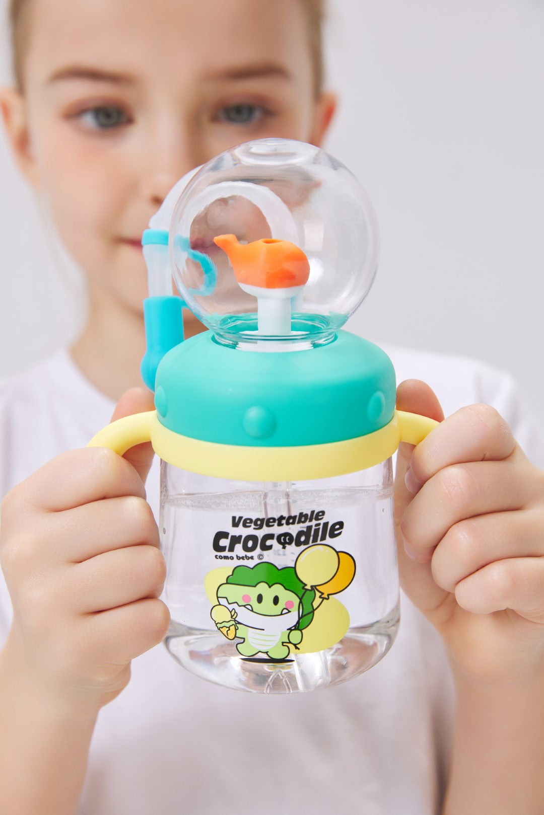 Child holding COMO Ball Tritan Kids Cup 10oz with Crocodile design - Spring Family Hydration Bundle by COMOBEBE